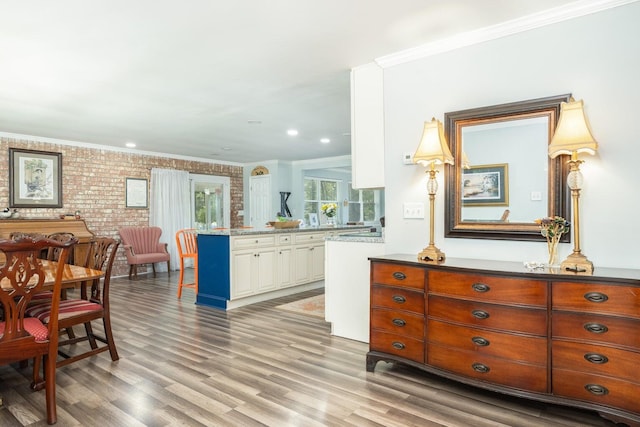 interior space with brick wall, hardwood / wood-style floors, and ornamental molding