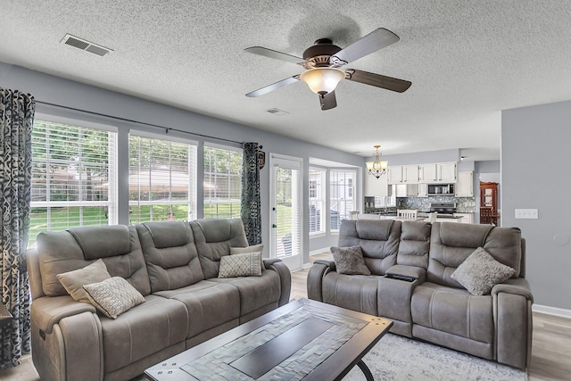 100 Conset Bay Ct, Goose Creek, SC 29445 - living room with a chandelier, a textured ceiling, a ceiling fan, light wood-style floors, and healthy amount of natural light