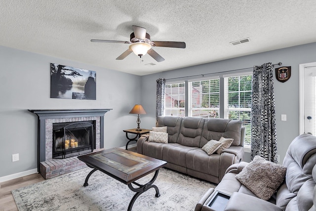 100 Conset Bay Ct, Goose Creek, SC 29445 - living room featuring light wood-type flooring, ceiling fan, a brick fireplace, a textured ceiling, and baseboards