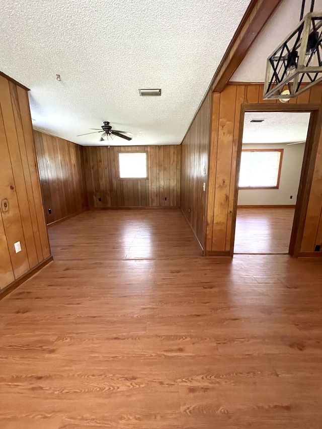 6287 Sniders Hwy, Walterboro, SC 29488 - unfurnished room featuring a textured ceiling, ceiling fan, light wood-type flooring, wooden walls, and baseboards