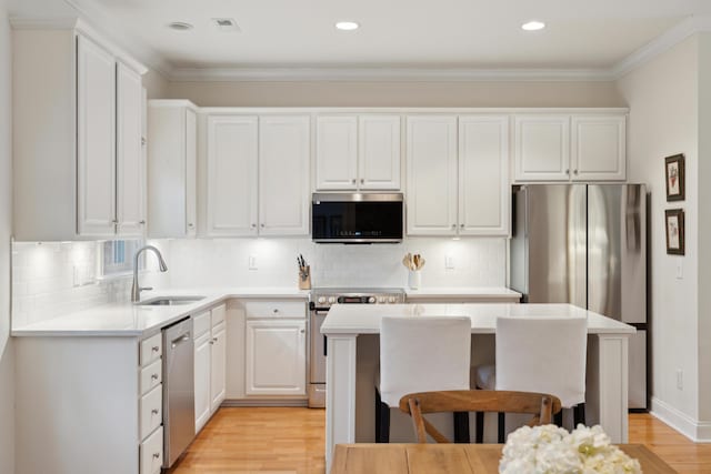 kitchen featuring appliances with stainless steel finishes, sink, a kitchen island, and white cabinets