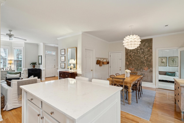 kitchen featuring ornamental molding, light hardwood / wood-style floors, a kitchen island, and white cabinets