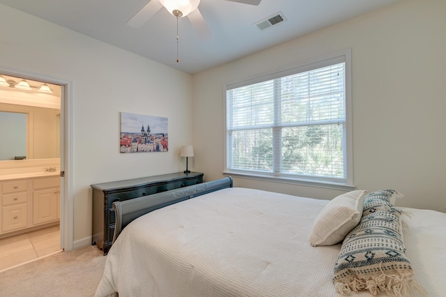 bedroom featuring ensuite bathroom, light tile patterned flooring, light carpet, a ceiling fan, and visible vents