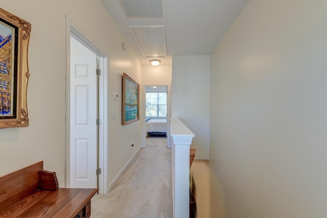 hallway with attic access, visible vents, baseboards, light colored carpet, and an upstairs landing