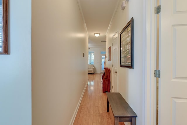 hall with crown molding, light wood-style flooring, and baseboards