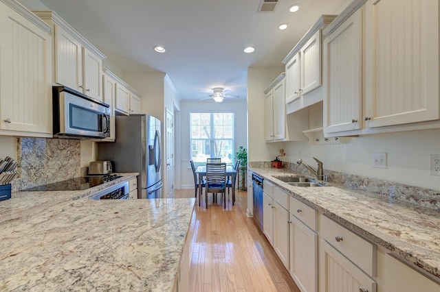 kitchen with visible vents, light stone counters, stainless steel appliances, and a sink