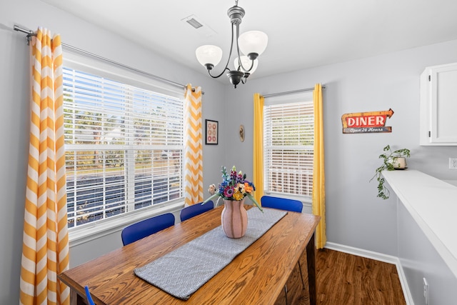 dining area with a chandelier, visible vents, baseboards, and dark wood-style floors