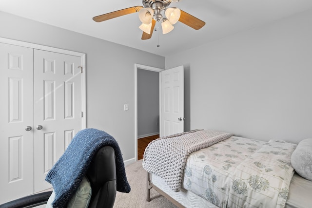 bedroom with light carpet, ceiling fan, a closet, and baseboards