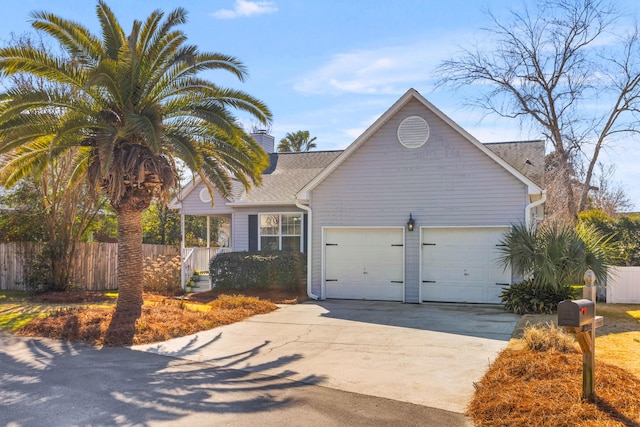 view of front of property with a garage, driveway, a chimney, and fence