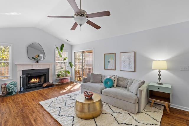 living area featuring visible vents, a fireplace with flush hearth, a ceiling fan, vaulted ceiling, and wood finished floors