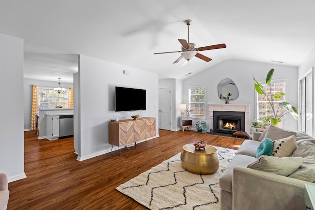 living room featuring dark wood-style floors, lofted ceiling, plenty of natural light, and a lit fireplace