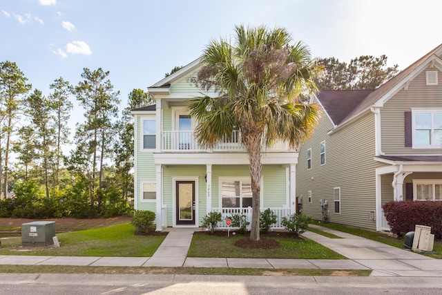 view of front facade with a balcony, covered porch, and a front lawn