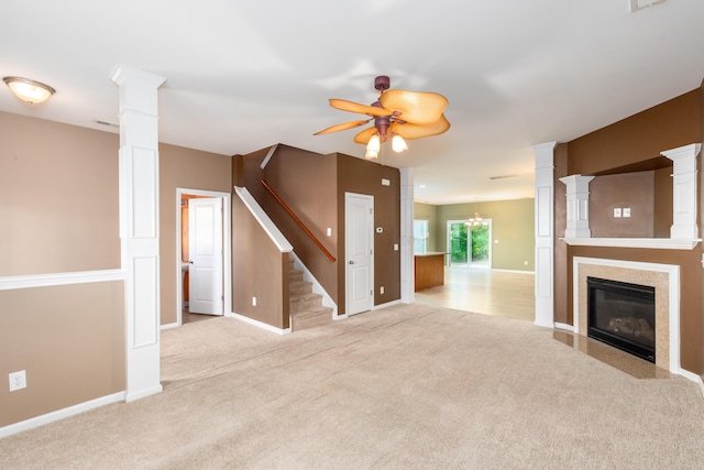 unfurnished living room with ornate columns, ceiling fan with notable chandelier, and light carpet