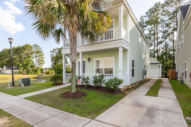 view of front of property with a porch, a front yard, a garage, an outbuilding, and a balcony