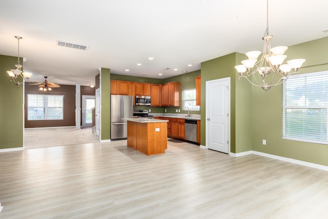 kitchen featuring pendant lighting, sink, stainless steel appliances, a center island, and light wood-type flooring