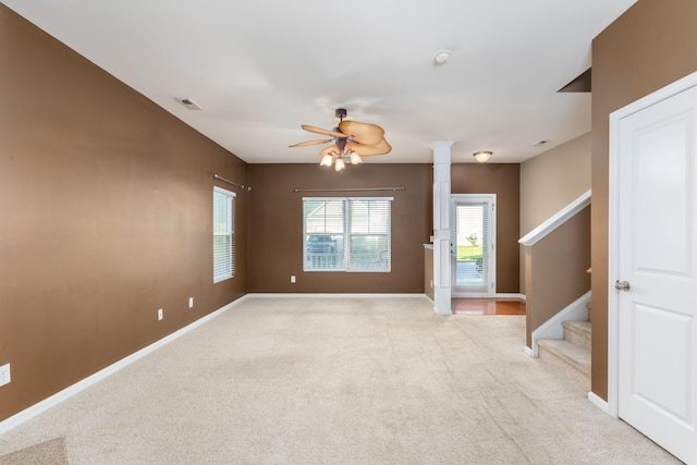 spare room featuring decorative columns, light colored carpet, and ceiling fan