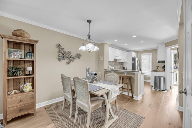 dining room featuring ornamental molding, recessed lighting, light wood-style flooring, and baseboards