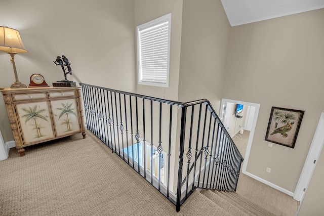 hallway featuring lofted ceiling, carpet, and baseboards