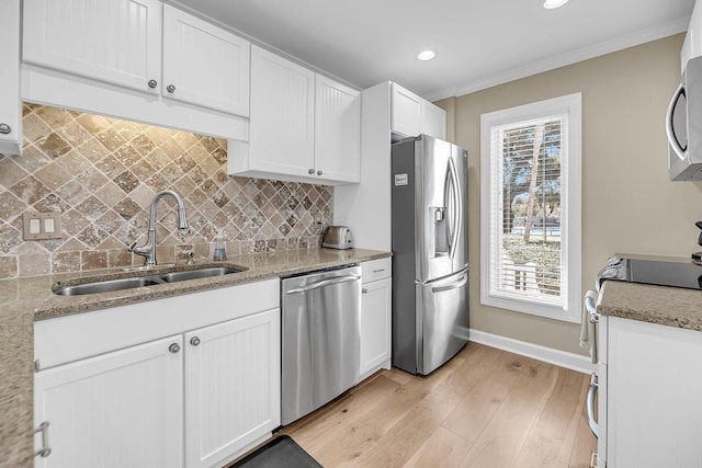 kitchen featuring crown molding, stainless steel appliances, light wood-style floors, white cabinetry, and a sink