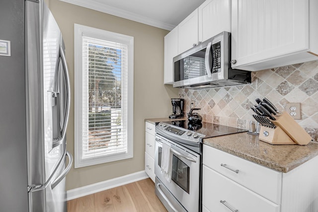 kitchen featuring light wood-style flooring, appliances with stainless steel finishes, backsplash, ornamental molding, and a wealth of natural light