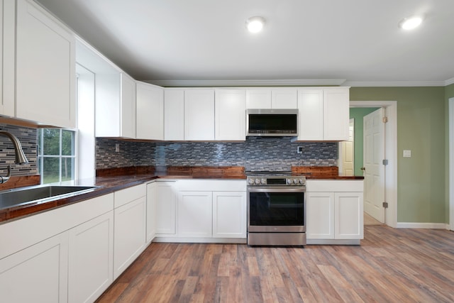 kitchen featuring white cabinetry, appliances with stainless steel finishes, wood-type flooring, and sink