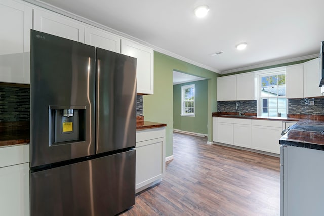 kitchen featuring stainless steel refrigerator with ice dispenser, white cabinets, wood-type flooring, and tasteful backsplash