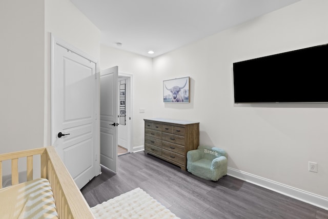 bedroom with hardwood / wood-style floors, a nursery area, and a closet