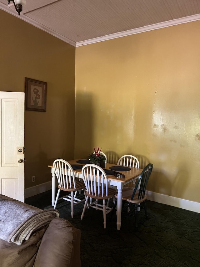 dining space featuring dark colored carpet and crown molding