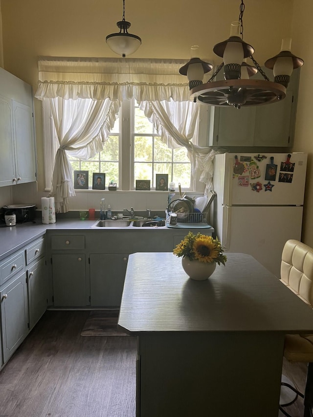 kitchen with white refrigerator, dark wood-type flooring, sink, a kitchen island, and gray cabinetry