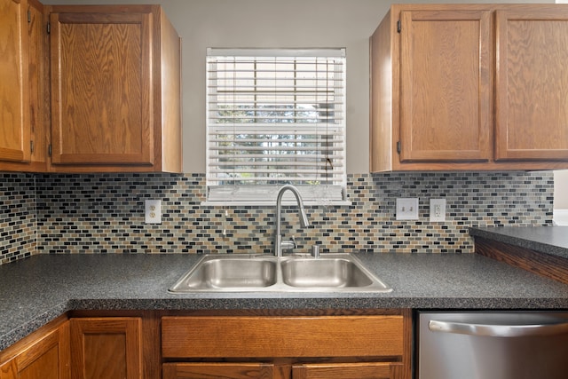 kitchen featuring dishwasher, dark countertops, a sink, and decorative backsplash