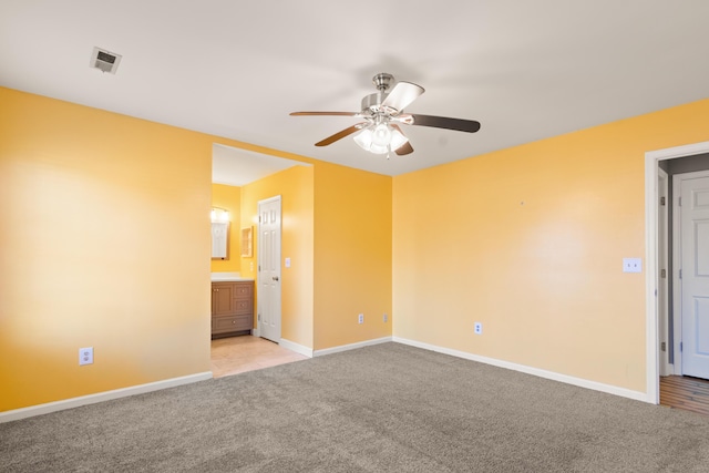 unfurnished bedroom with baseboards, connected bathroom, visible vents, and light colored carpet