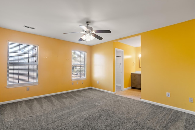 unfurnished bedroom featuring visible vents, ensuite bathroom, a ceiling fan, carpet flooring, and baseboards