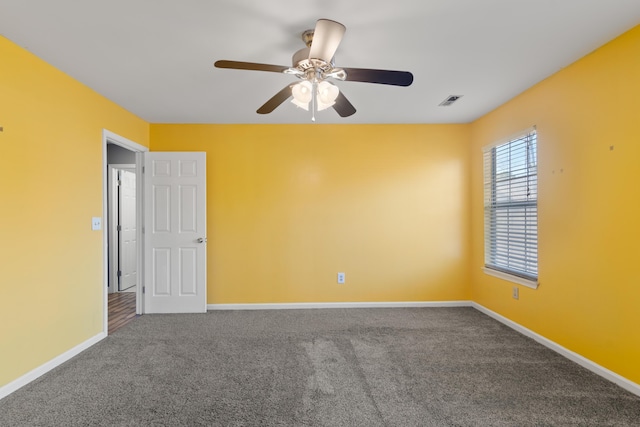 unfurnished room with carpet floors, visible vents, ceiling fan, and baseboards