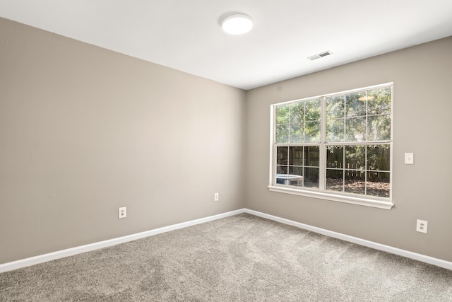 spare room with carpet flooring, visible vents, and baseboards