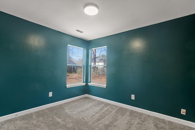 carpeted spare room with visible vents and baseboards