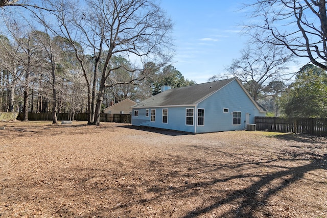 rear view of house featuring a chimney, cooling unit, and fence