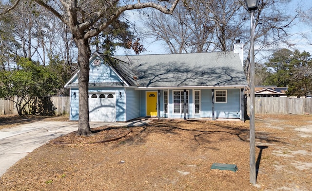 view of front of property featuring covered porch, concrete driveway, fence, and a garage