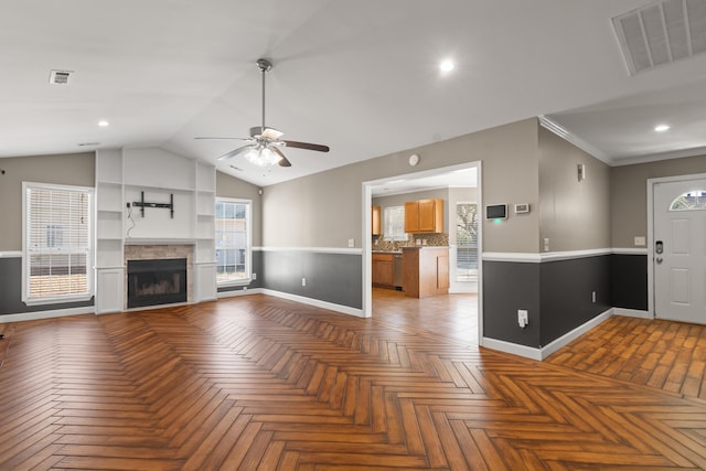 unfurnished living room with lofted ceiling, visible vents, a fireplace, and baseboards