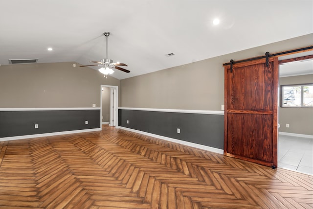 spare room featuring lofted ceiling, ceiling fan, a barn door, visible vents, and baseboards