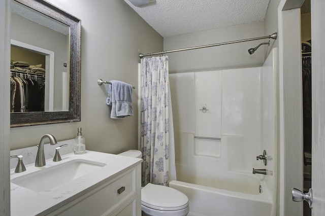 full bathroom featuring vanity, shower / bath combo with shower curtain, a textured ceiling, a walk in closet, and toilet