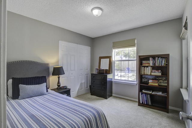 carpeted bedroom with baseboards, a closet, and a textured ceiling