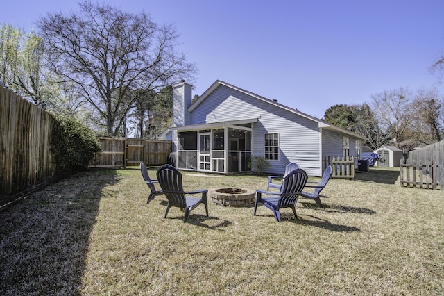 back of property featuring a fire pit, a fenced backyard, a sunroom, and a chimney