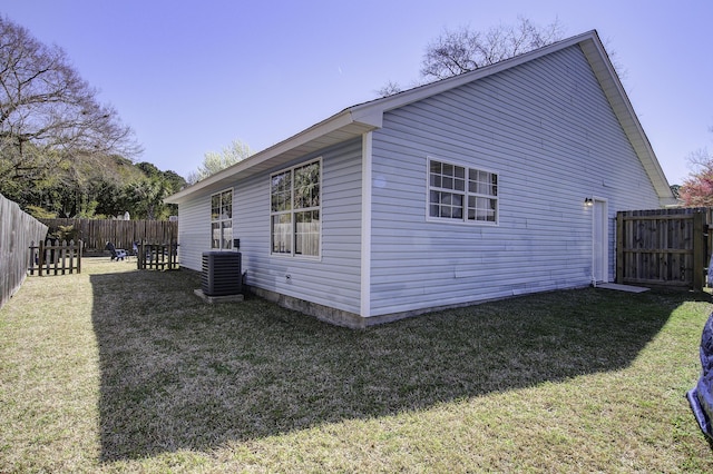 view of side of home with cooling unit, a yard, and a fenced backyard