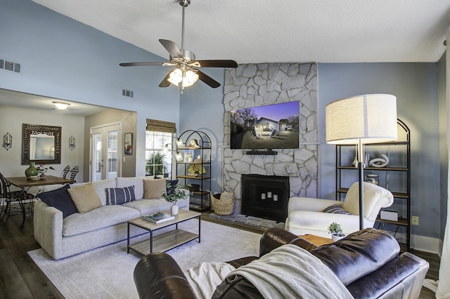 living area with a stone fireplace, wood finished floors, visible vents, and french doors