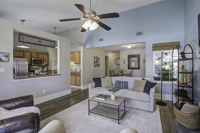 living area with dark wood finished floors, baseboards, visible vents, and high vaulted ceiling