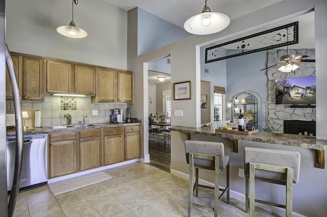 kitchen with a sink, appliances with stainless steel finishes, a kitchen breakfast bar, brown cabinets, and backsplash