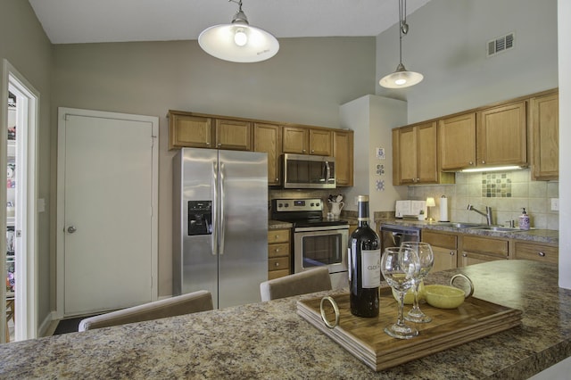 kitchen featuring brown cabinetry, visible vents, a sink, decorative backsplash, and appliances with stainless steel finishes