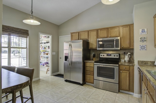 kitchen with brown cabinets, appliances with stainless steel finishes, light tile patterned floors, decorative backsplash, and vaulted ceiling