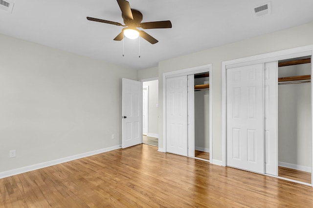 unfurnished bedroom with ceiling fan, light wood-type flooring, and multiple closets