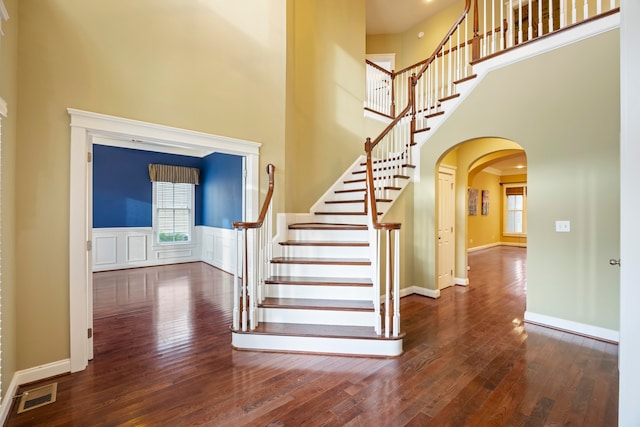 stairs with a towering ceiling and hardwood / wood-style floors